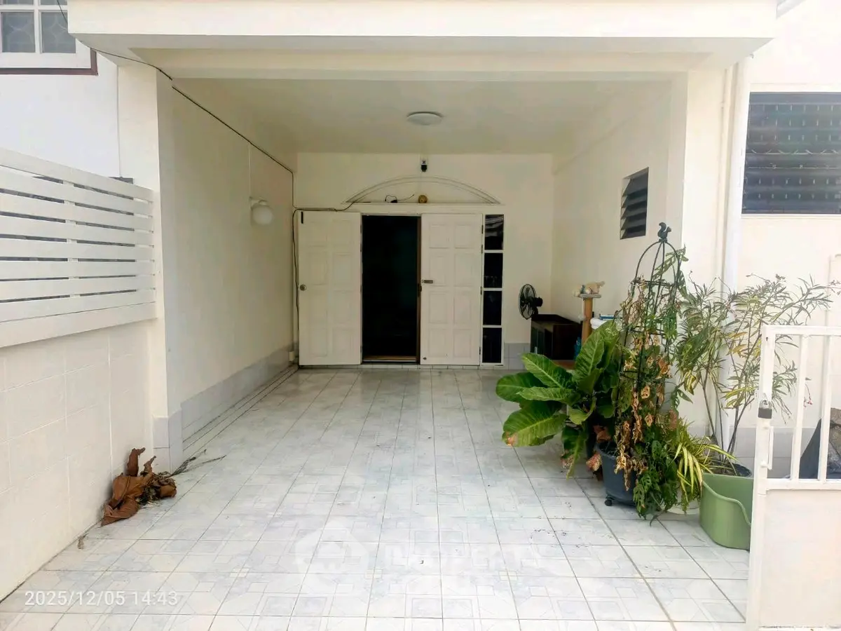 Spacious covered entrance with tiled flooring and potted plants