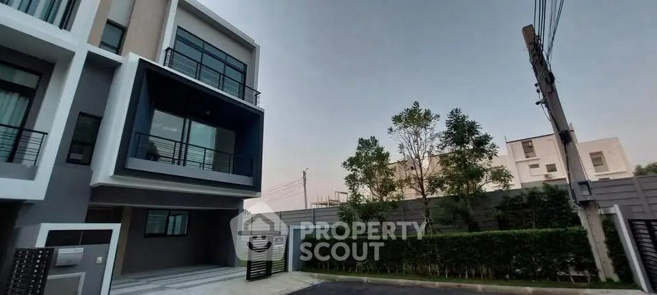 Modern townhouse exterior with sleek design and lush greenery in a serene neighborhood.