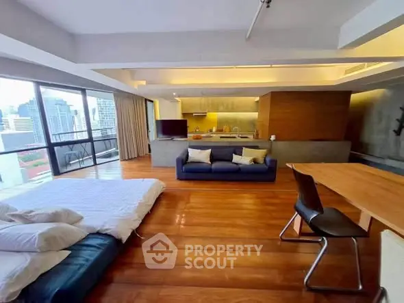 Spacious open-plan living room with city view, modern kitchen, and cozy seating area.