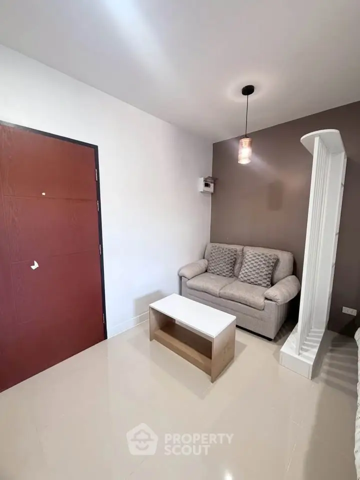 Cozy living room with modern sofa and stylish lighting in a compact apartment.