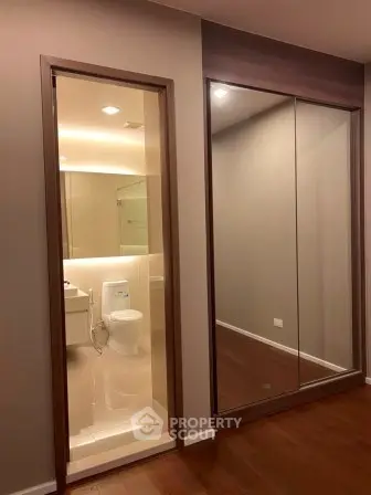 Modern bathroom with sleek design and mirrored closet in a stylish apartment.