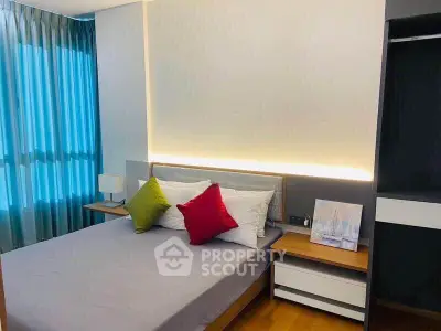 Modern bedroom with stylish lighting and colorful pillows in a cozy apartment.