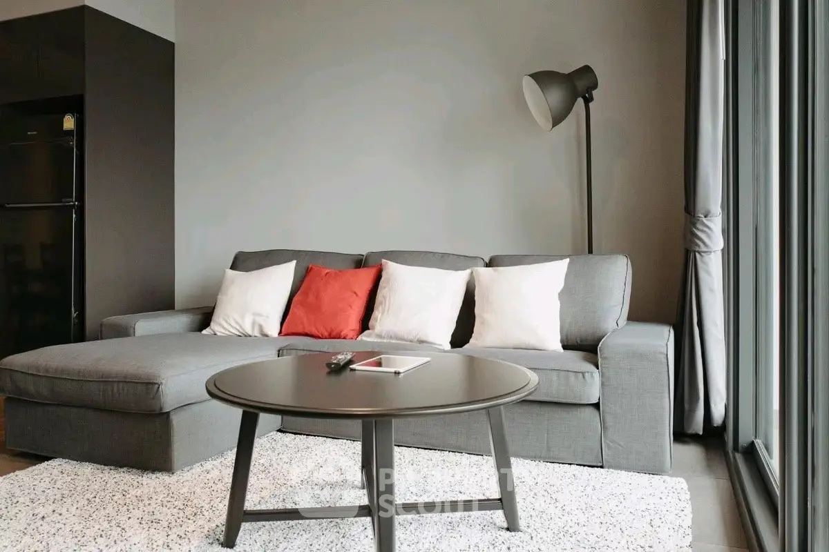 Modern living room with stylish gray sofa, floor lamp, and large windows for natural light.