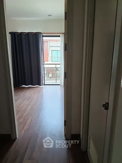Spacious room with wooden flooring and large window with balcony view