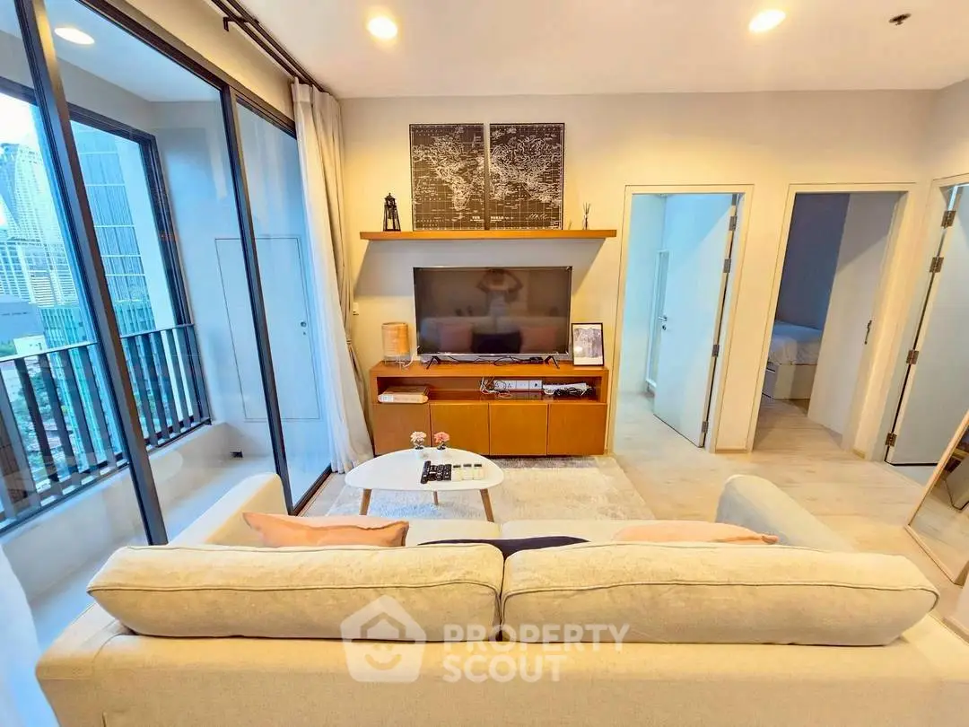 Modern living room with city view, cozy sofa, and stylish decor in high-rise apartment.