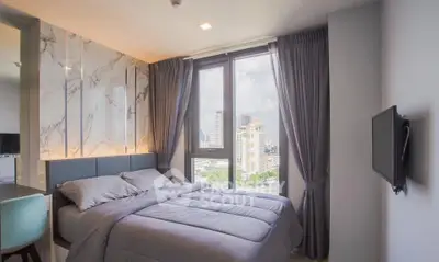Modern bedroom with large windows offering city views, elegant decor, and cozy ambiance.