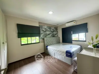 Spacious bedroom with modern decor and large windows offering natural light.