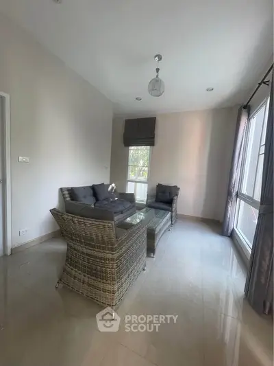 Cozy living room with modern wicker furniture and large windows for natural light.