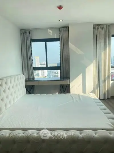 Spacious bedroom with large windows offering a stunning city view, featuring a luxurious bed and elegant curtains.