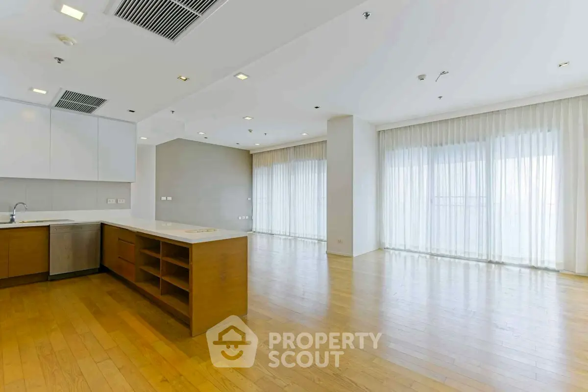 Spacious open-plan living area with hardwood floors and large windows