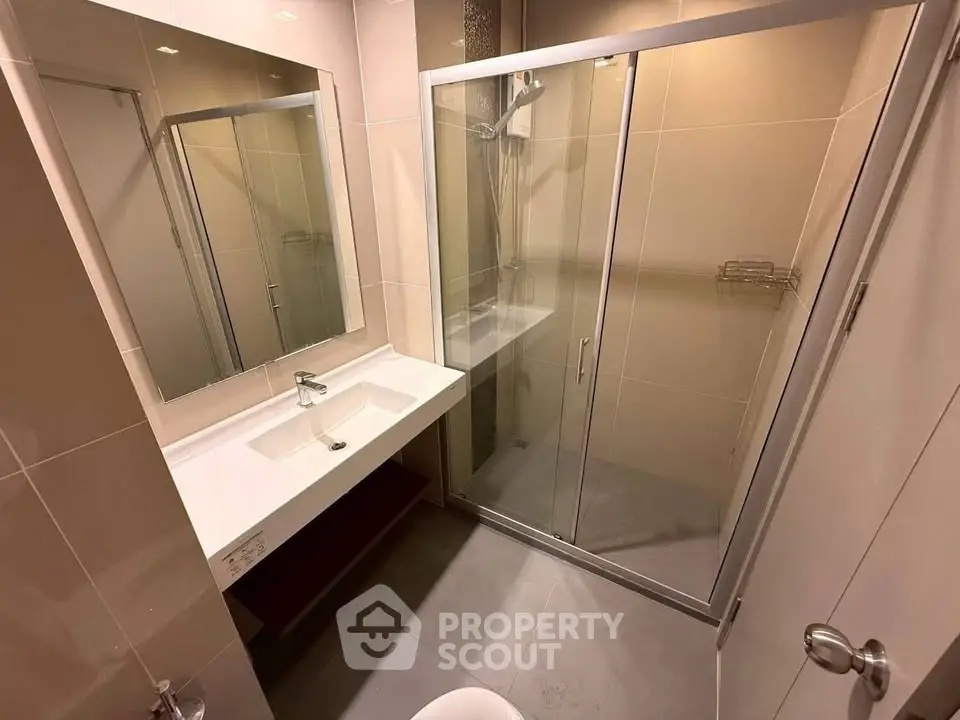 Modern bathroom with glass shower enclosure and sleek vanity in a contemporary apartment.