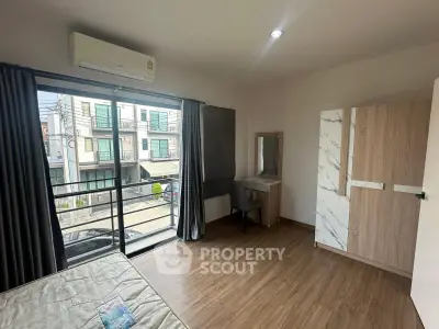 Spacious bedroom with large window and modern furnishings in a stylish apartment.