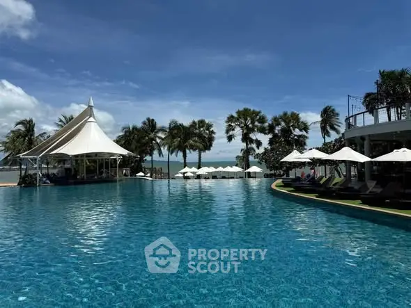 Luxurious beachfront pool with palm trees and ocean view, perfect for relaxation and leisure.