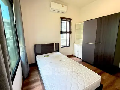Modern bedroom with large window, air conditioning, and sleek wardrobe in a bright apartment.