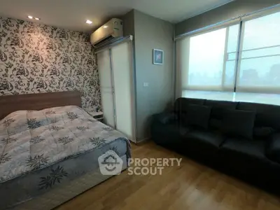 Modern bedroom with stylish wallpaper and cozy seating area in a high-rise apartment.
