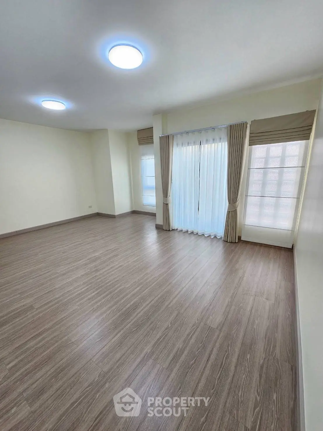 Spacious empty room with large windows and elegant curtains, perfect for customization.