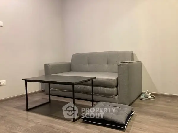 Minimalist living room with gray sofa and modern coffee table on wooden floor.