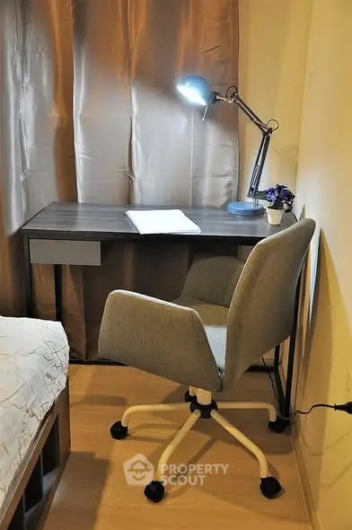 Cozy study nook with desk, chair, and lamp in modern apartment.