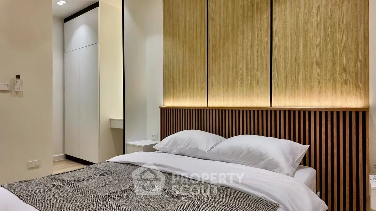 Modern bedroom with stylish wooden paneling and cozy bedding