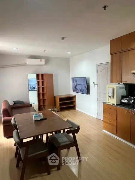 Modern living room with wooden furniture and wall-mounted TV in cozy apartment.