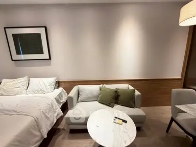 Modern studio apartment with cozy bed, stylish sofa, and elegant decor.