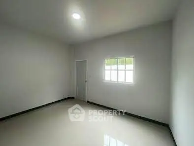Spacious empty room with bright window and sleek flooring, ideal for customization.
