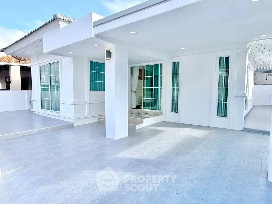 Modern white exterior with large windows and spacious patio, perfect for outdoor living.