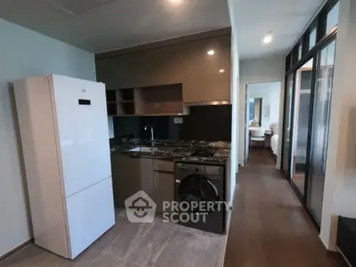 Modern kitchen with sleek cabinets, fridge, and washing machine in open layout apartment.