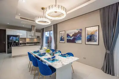 Luxurious dining area with elegant chandelier and modern kitchen in open layout design.