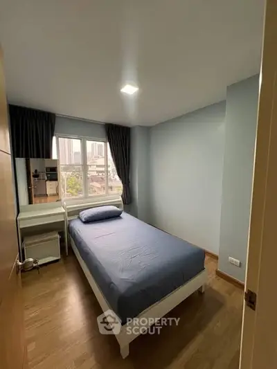 Cozy bedroom with single bed and city view, perfect for urban living.