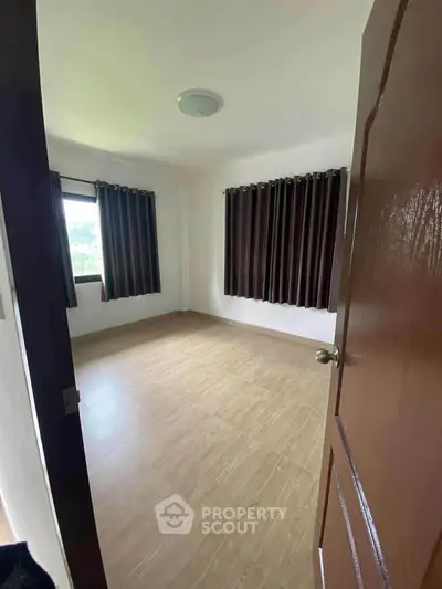 Spacious empty bedroom with large windows and elegant curtains, perfect for customization.