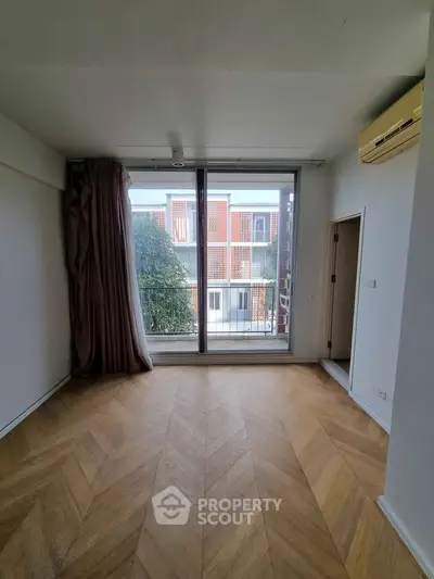 Spacious room with large window and wooden flooring, perfect for natural light lovers.