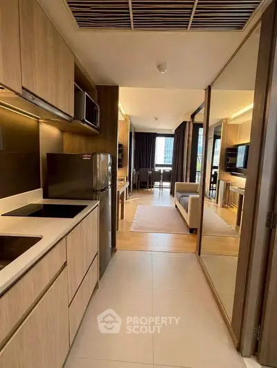 Modern open-layout kitchen with sleek cabinetry and stainless steel appliances leading to a stylish living area.