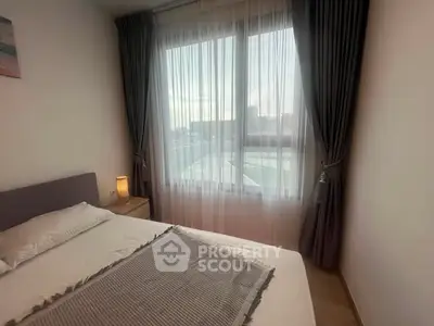 Cozy bedroom with large window and elegant curtains, offering a serene ambiance and natural light.