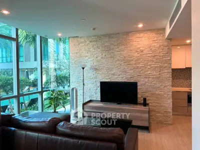 Luxurious living room with modern decor and large windows offering a stunning view of lush greenery.