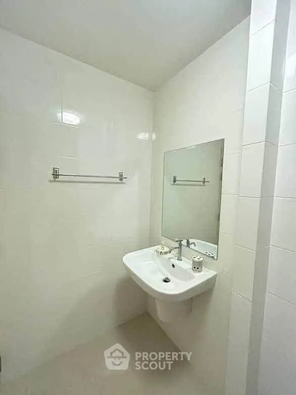 Modern minimalist bathroom with sleek white tiles and a wall-mounted sink.