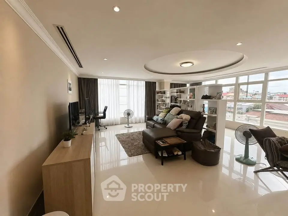 Spacious living room with modern decor and large windows offering city views.