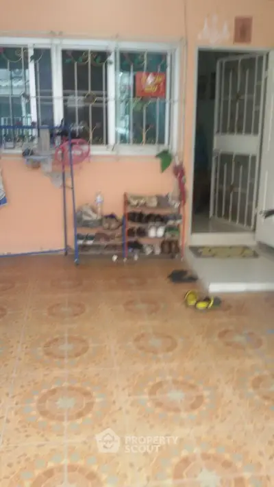 Charming home entrance with tiled flooring and shoe rack, offering a warm welcome.