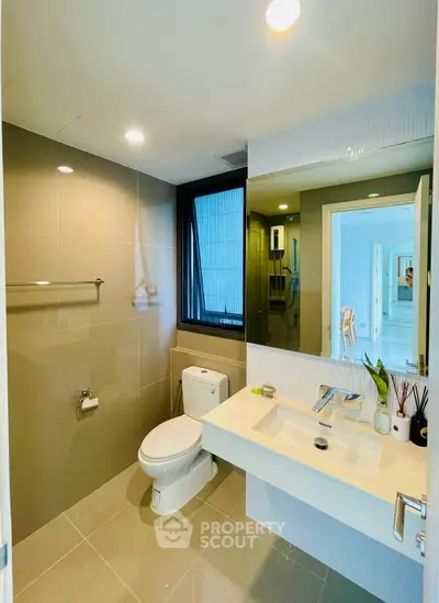 Modern bathroom with sleek fixtures and large mirror in a contemporary home.