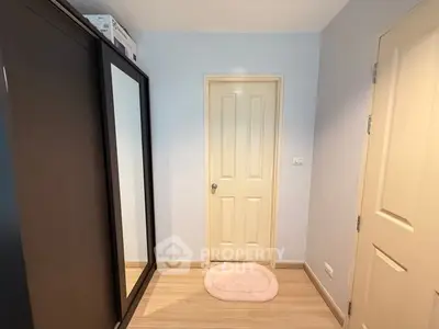 Cozy small bedroom with mirrored wardrobe and wooden flooring