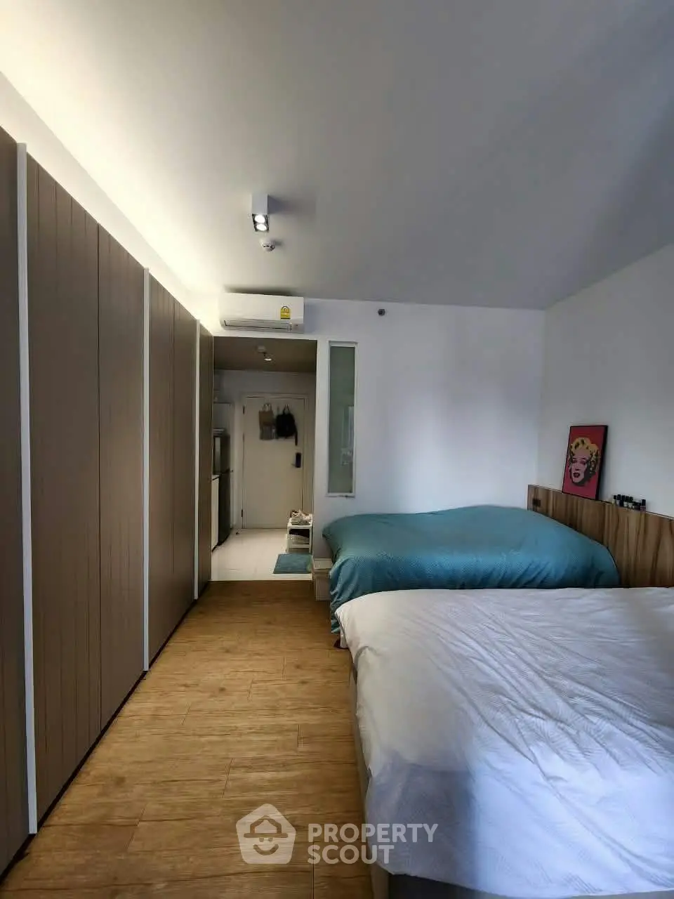Modern bedroom with two beds, wooden flooring, and stylish decor in a cozy apartment.