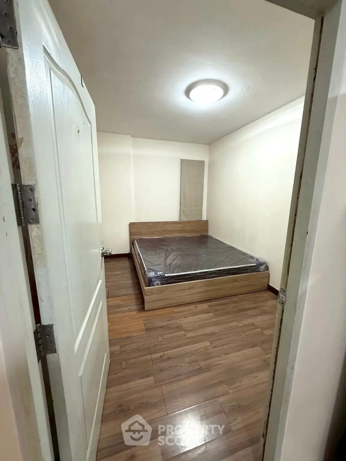 Cozy bedroom with wooden flooring and modern bed frame, perfect for restful nights.