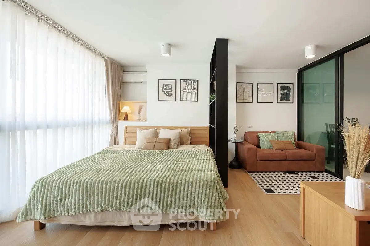 Modern studio apartment with cozy bedroom and stylish living area, featuring large windows and contemporary decor.