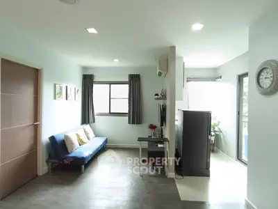 Modern living room with stylish decor and natural light, featuring a cozy sofa and sleek TV setup.