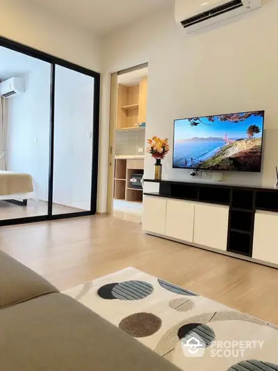 Modern living room with stylish decor and open view into bedroom, featuring sleek TV setup.