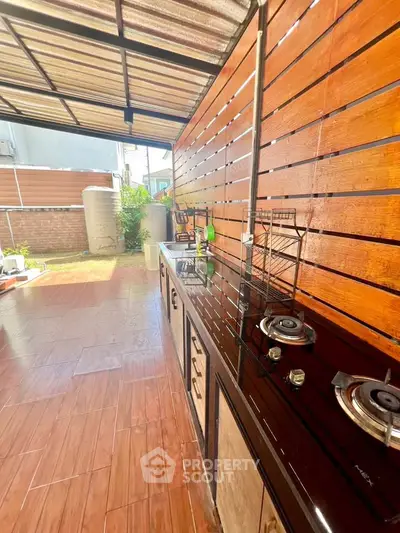 Spacious outdoor kitchen with modern gas stove and wooden paneling