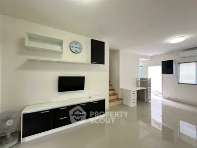 Modern living room with sleek black and white furniture and wall-mounted TV