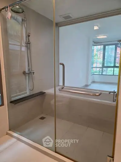 Spacious bathroom with modern shower and bathtub in a bright apartment.