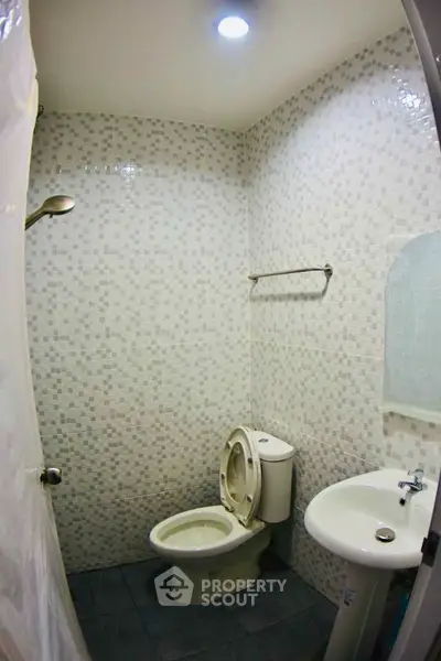 Compact bathroom with tiled walls and basic fixtures