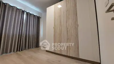 Spacious bedroom with elegant wooden wardrobe and floor-to-ceiling curtains.